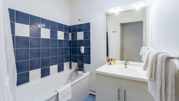 A bathroom with a bathtub, a sink, and a mirror.