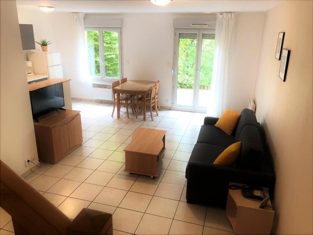 A modern living room with a sofa, a TV, a dining table, and chairs.