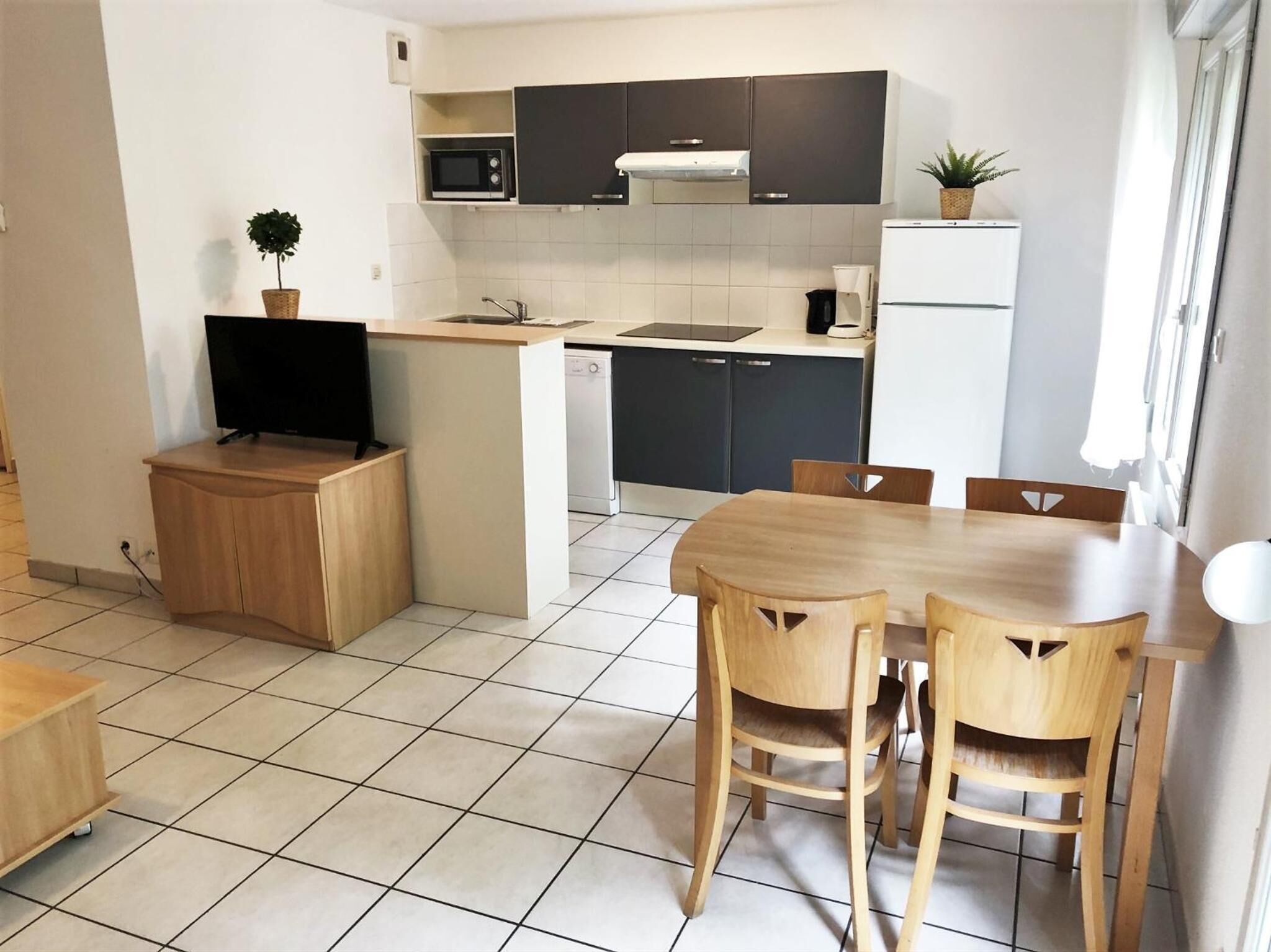 A compact kitchen with a dining area, a microwave, a sink, and a refrigerator.