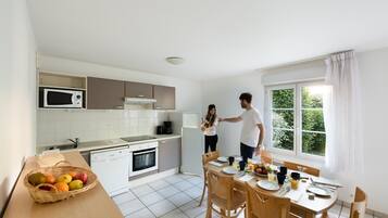 A modern kitchen with white cabinets, a microwave, and a dining area with a table set for two.