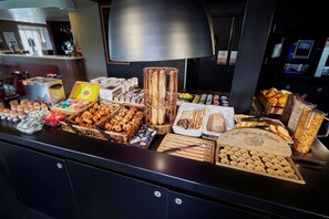 Ein Buffet mit verschiedenen Speisen, darunter Brot, Gebäck und Beilagen.