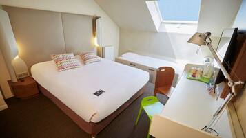 Une chambre d’hôtel équipée d’un lit, d’une table de chevet, d’un bureau, d’une chaise et d’une lucarne.