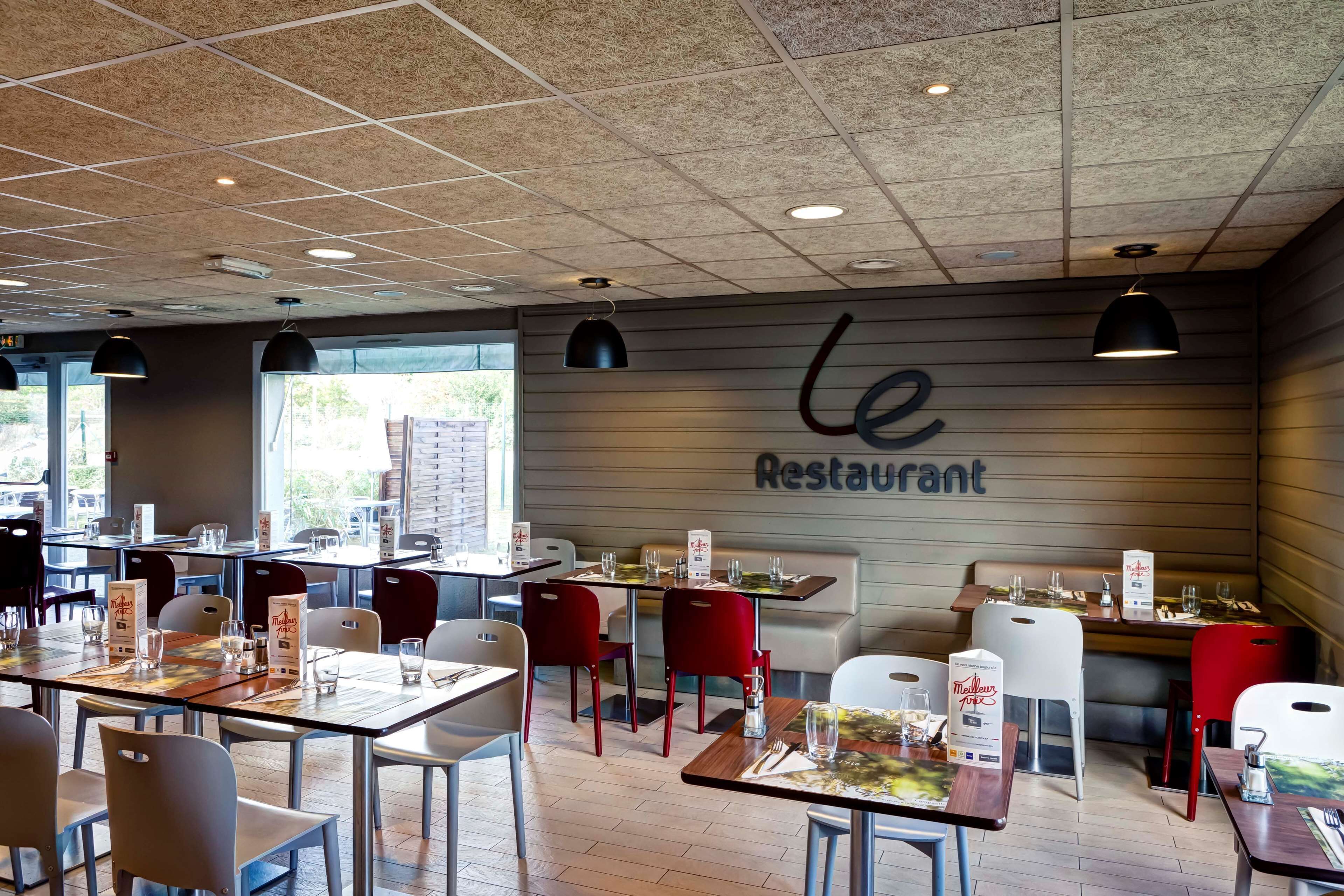 L’intérieur d’un restaurant, avec des tables, des chaises et une enseigne indiquant « Le Restaurant ».