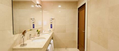 A modern bathroom with two sinks, a large mirror, and a shower.
