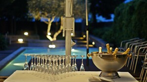 A table with a champagne bucket and glasses, a pool, and outdoor seating. - Hotel Bracara Augusta (Braga)