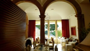 A dining area with tables, chairs, and a central column. - Hotel Bracara Augusta (Braga)