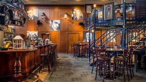 A bar area with wooden paneling, bar stools, and a staircase with blue railings. - Fletcher Wellness-Hotel Brabant-Mill (Mill)