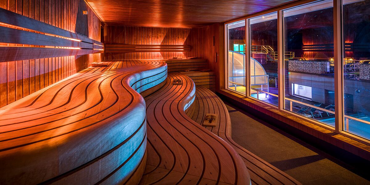 A modern interior with wooden curved benches and large windows.