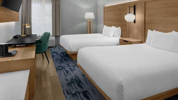 Habitación de hotel con dos camas, un escritorio con silla, televisión, lámpara y ventana con cortinas.