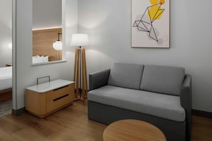 A modern hotel room with a grey sofa, wooden bedside table, and a floor lamp. - Fairfield Inn and Suites by Marriott Sacramento Elk Grove (Elk Grove)