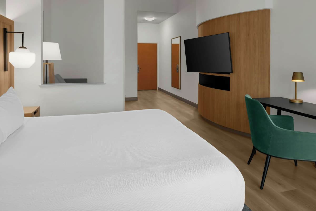 Une chambre d’hôtel avec un grand lit, un bureau avec une chaise, une télévision et un miroir.