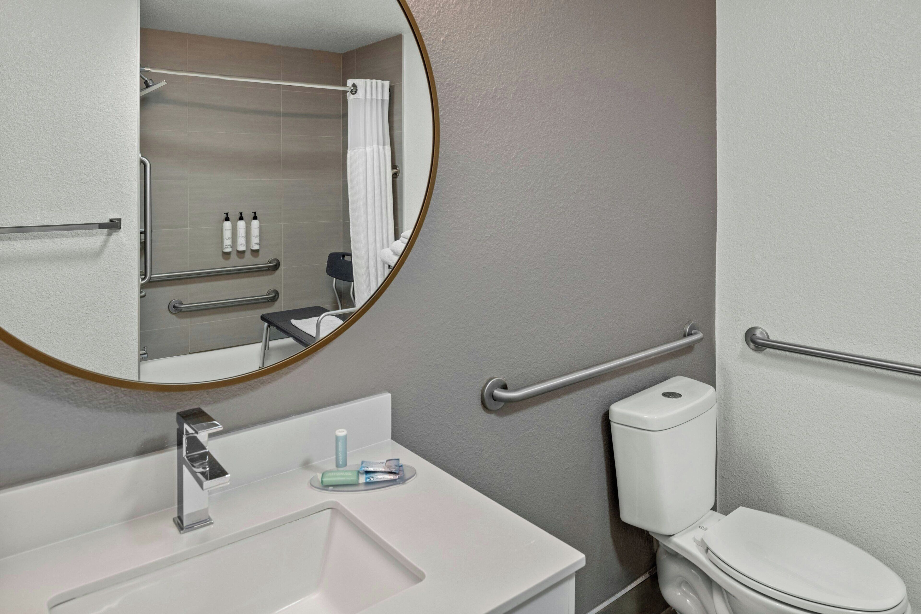 A bathroom with a white sink, a mirror, a toilet, and a shower area.