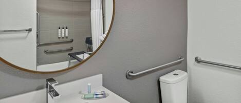 A bathroom with a white sink, a mirror, a toilet, and a shower area.