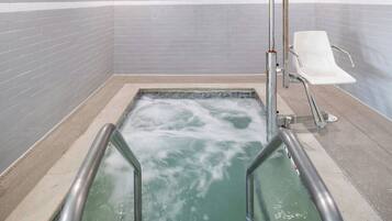 Relax in a serene hot tub surrounded by a stylish tile wall and comfortable seating.