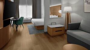 A hotel room with a bed, a desk, a TV, a chair, a sofa, a lamp, and a bedside table. - Fairfield Inn and Suites by Marriott Sacramento Elk Grove (Elk Grove)