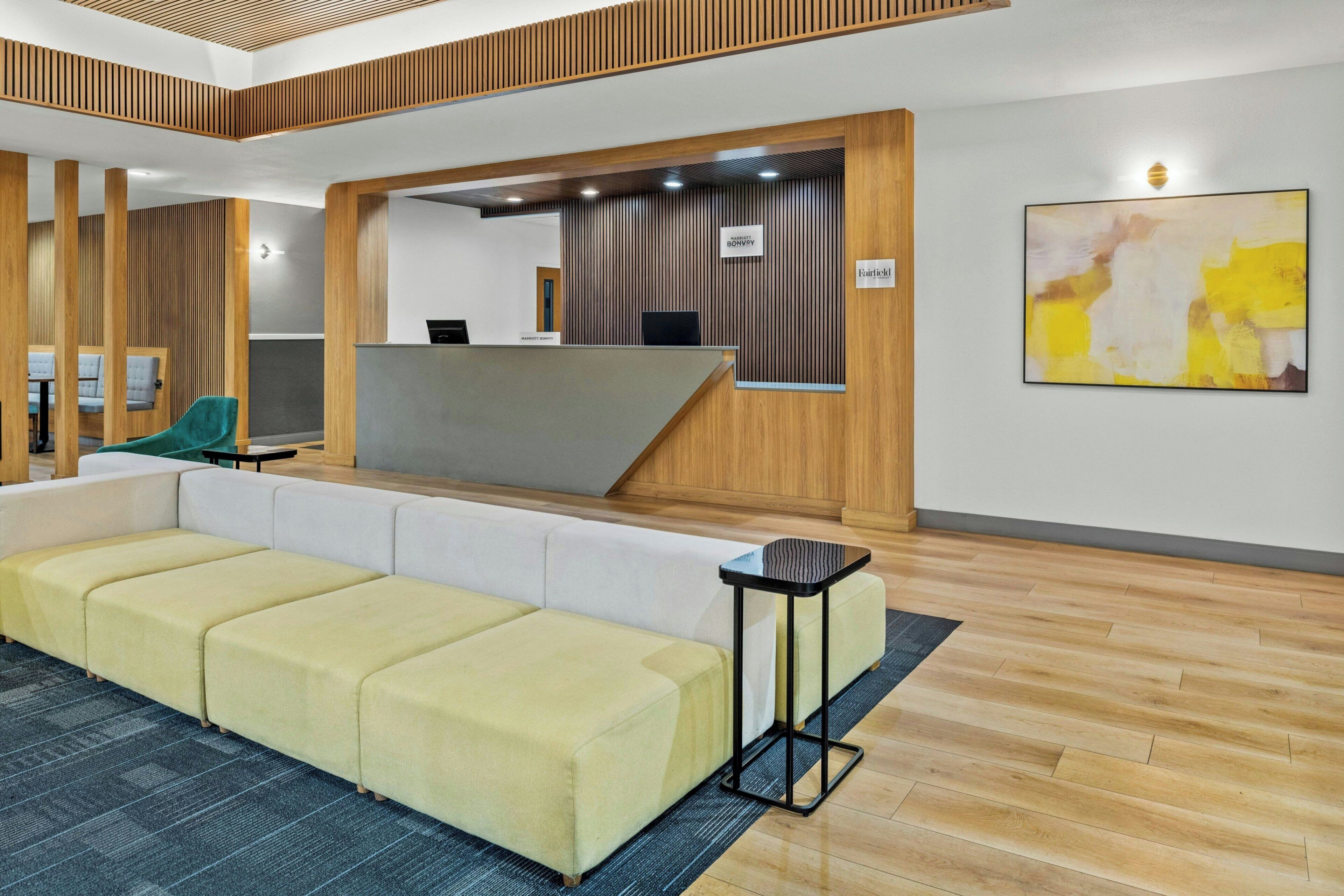 A reception area with a reception desk, a sofa, a small table, and a wall-mounted sign.