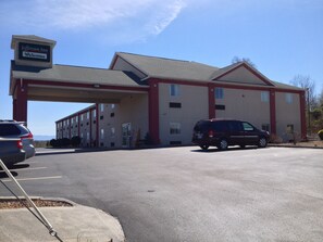 A Jefferson Inn with a red and beige building, a gas station, and a parking lot with cars. - Jefferson Inn Dandridge (Dandridge)