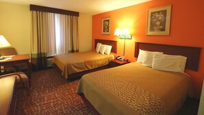 A hotel room with two beds, a desk, a chair, a lamp, and a window with curtains. - Jefferson Inn Dandridge (Dandridge)