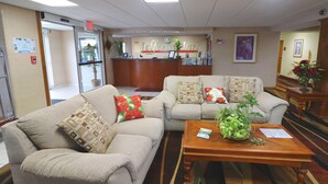 A hotel lobby with two beige sofas, a wooden coffee table, and a reception desk. - Jefferson Inn Dandridge (Dandridge)