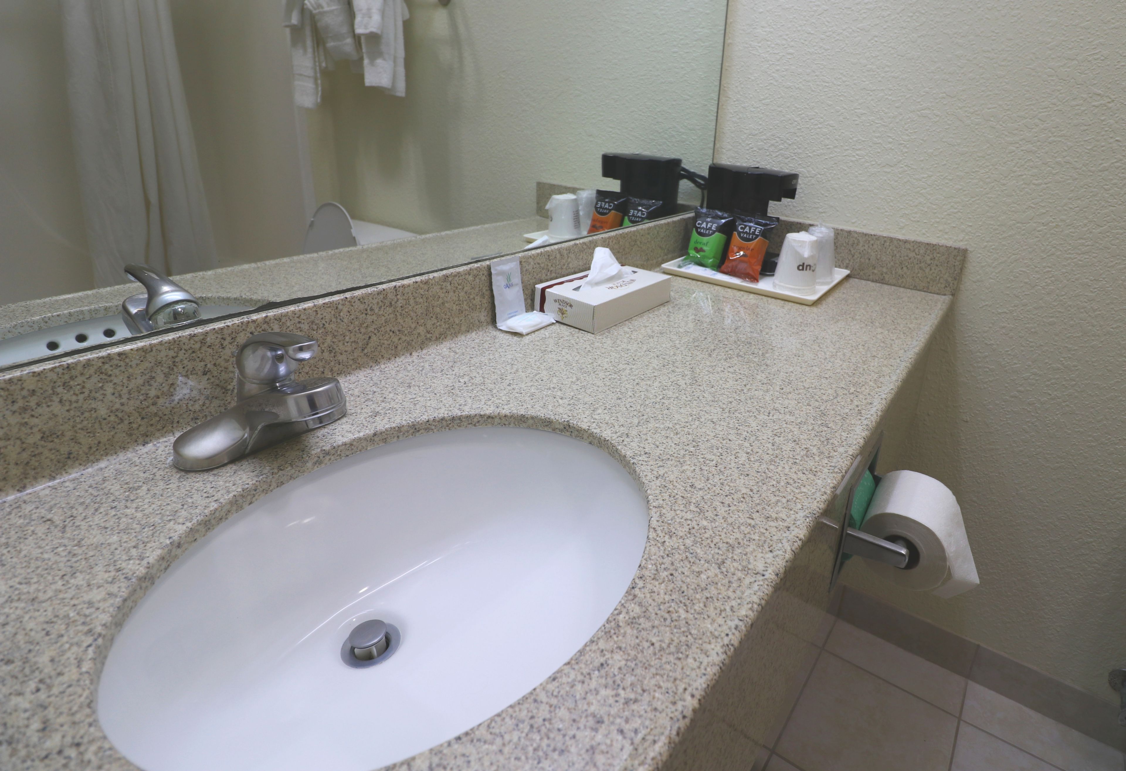 A bathroom sink with a mirror, a faucet, and a soap dispenser.