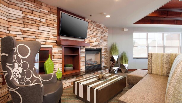 Una sala de estar moderna con una pared de piedra, un televisor de pantalla plana, chimenea y asientos cómodos.