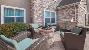 Un patio con mobiliario de mimbre, un hogar de piedra y una parrilla.