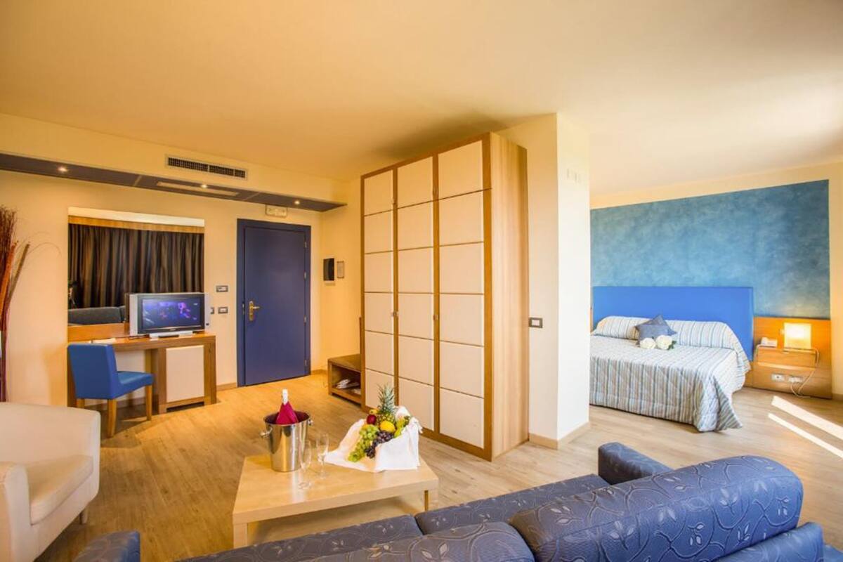 Una habitación de hotel con cama, televisor, escritorio y sofá.