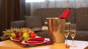 Una mesa con una bandeja de frutas, una botella de champán y dos copas.