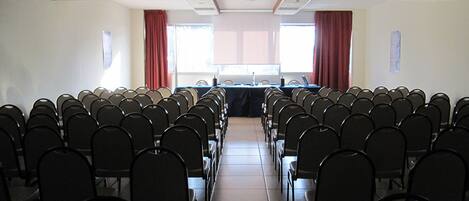 A conference room with rows of chairs facing a long table with a projector at the front.