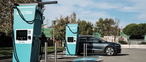 Two electric vehicle charging stations with a car parked nearby.