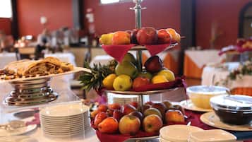 A buffet with a variety of fruits and a dessert on a tiered stand.