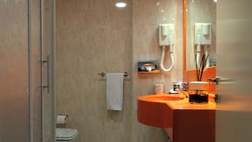 A modern bathroom with a glass shower enclosure, a white toilet, and an orange sink with a mirror above it.