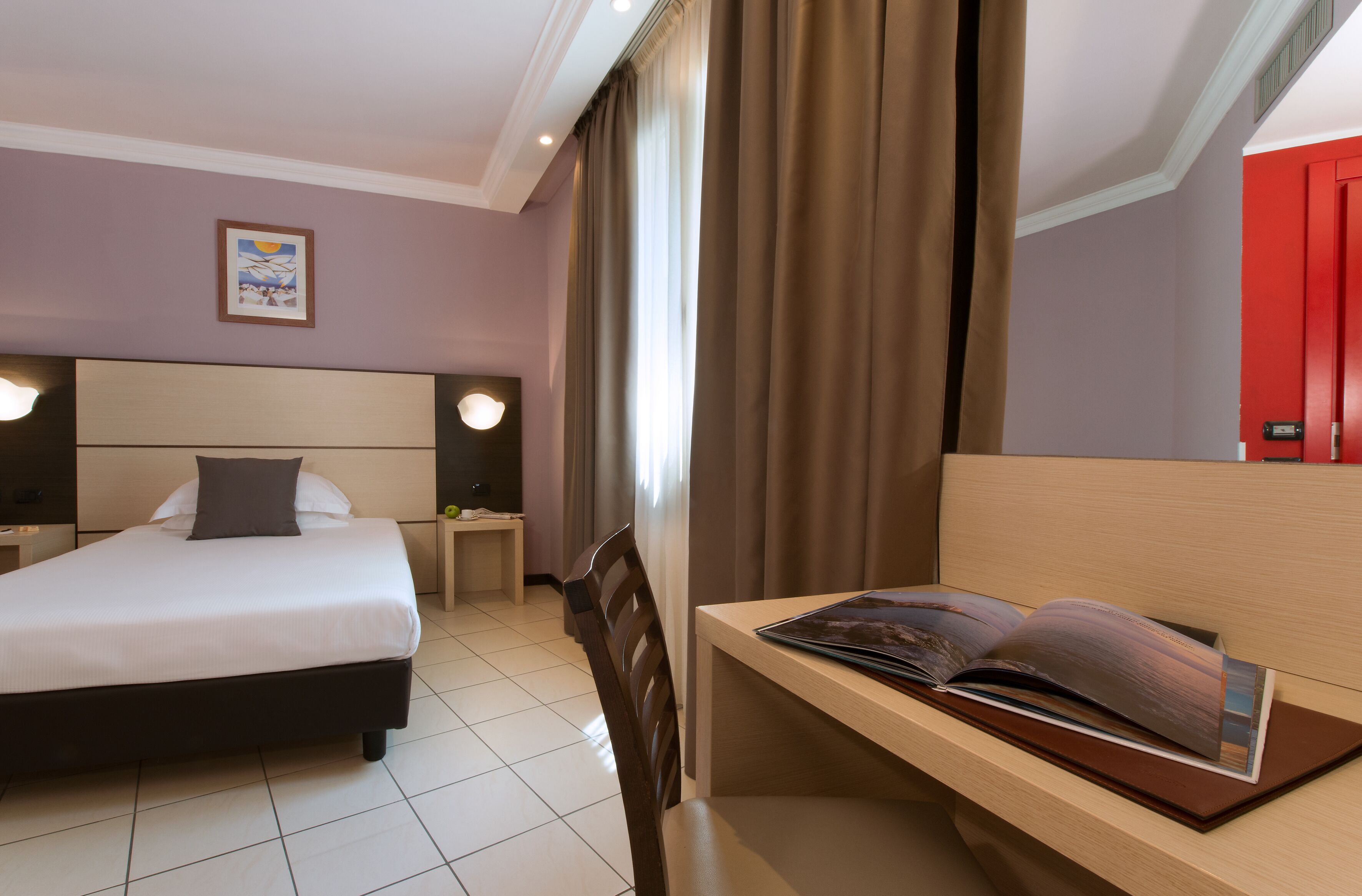 Una habitación de hotel con cama, mesitas de noche, un escritorio y una silla.