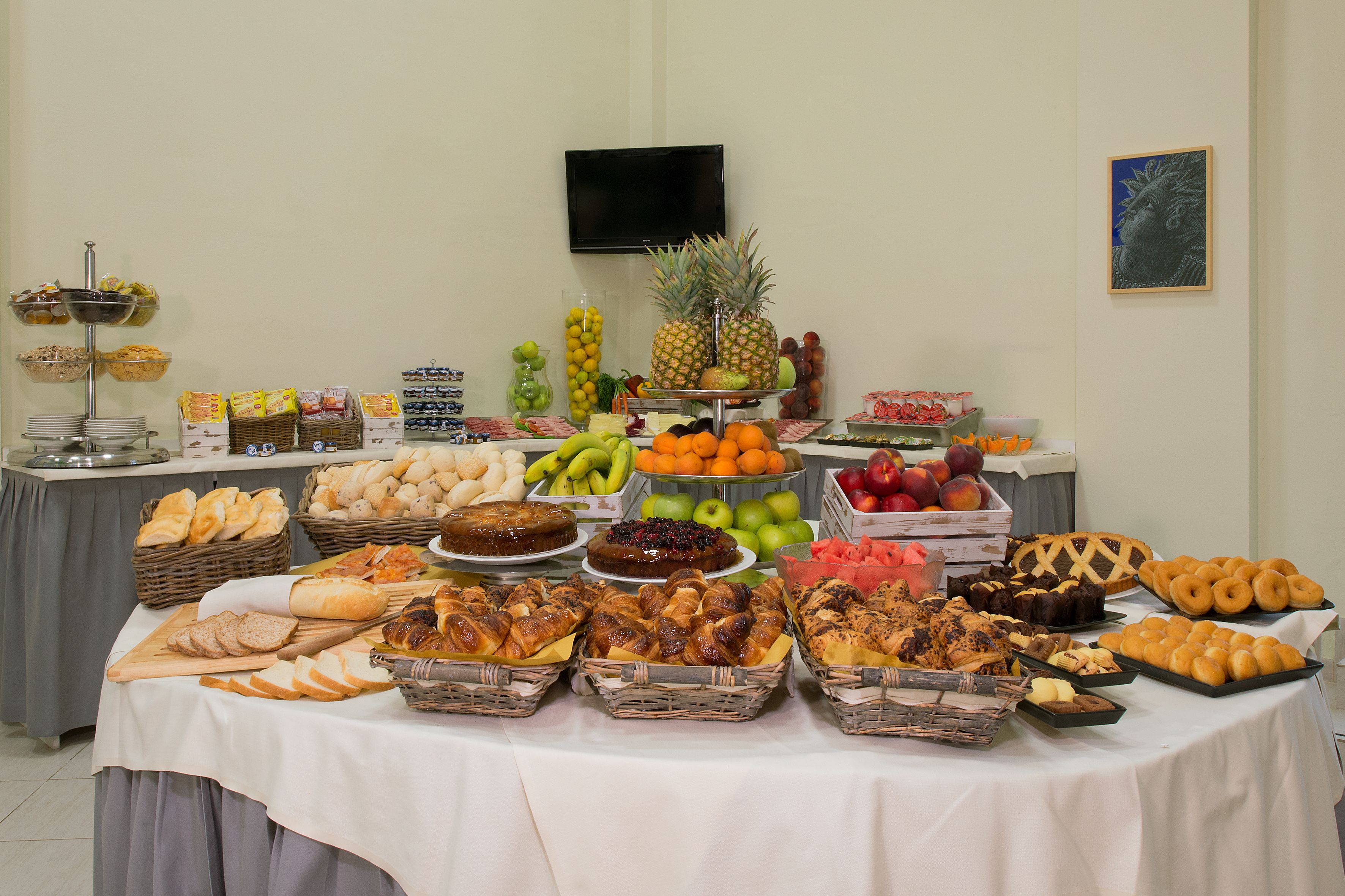 Ett buffébord med olika sorters mat, inklusive bröd, bakverk, frukt och desserter.
