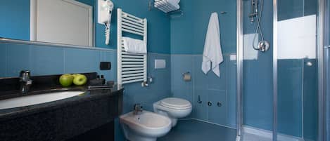 A bathroom with a sink, bidet, toilet, and glass-enclosed shower.