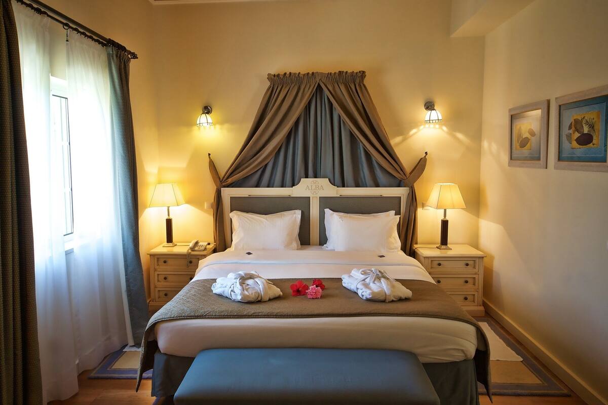 A neatly made bed with white linens, two bedside lamps, and a decorative headboard.