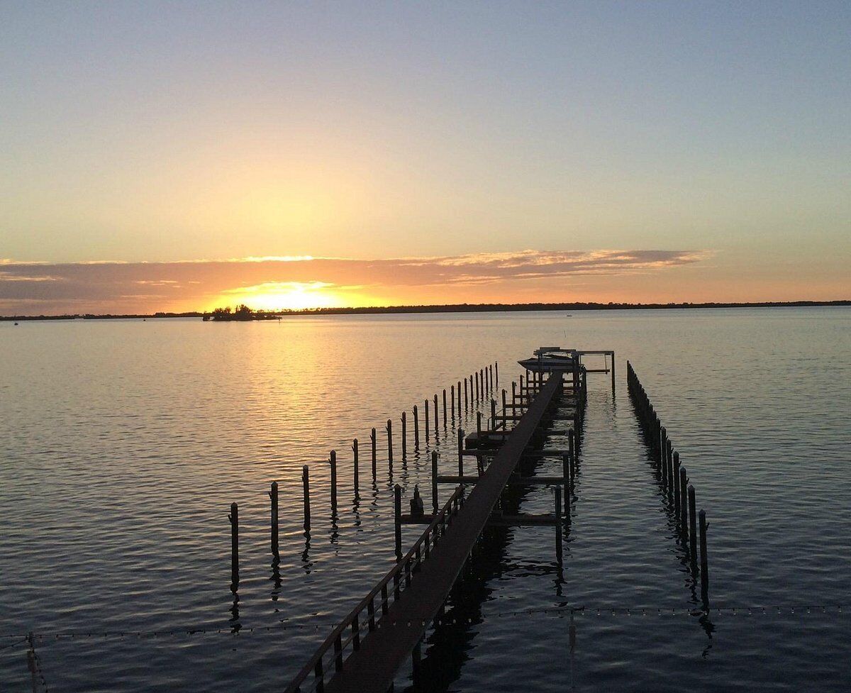 A pier extending into calm water with a sunset in the background.