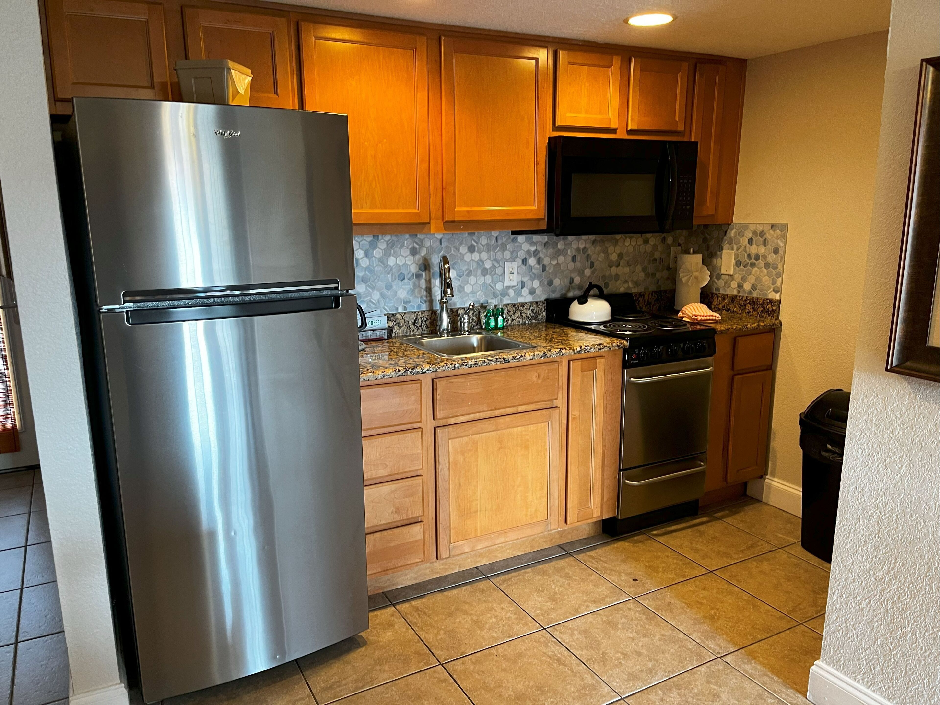 Una cocina con armarios de madera, un refrigerador de acero inoxidable, un microondas, una estufa y un lavavajillas.