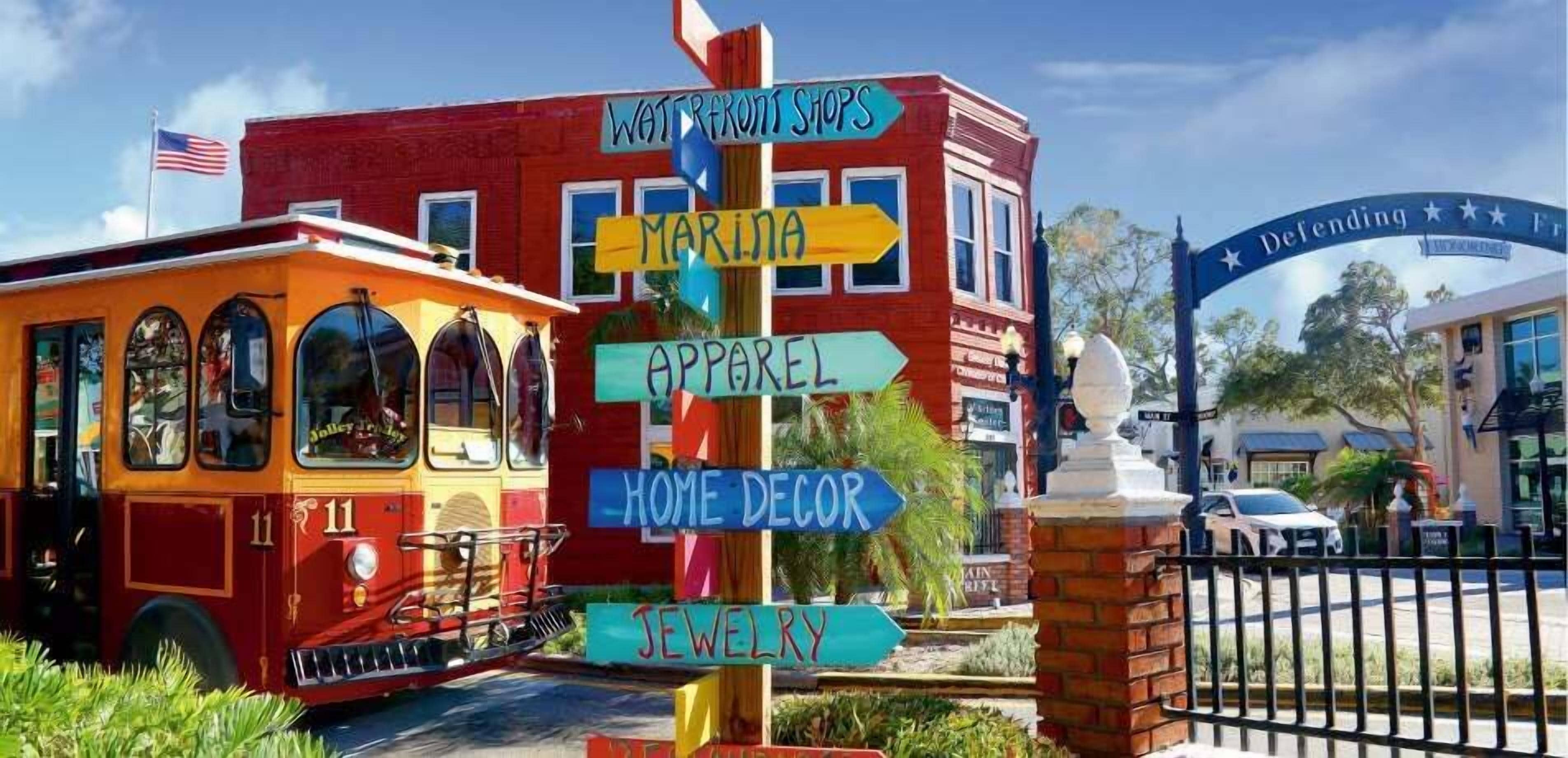 A colorful trolley with a signpost indicating directions to various shops such as Waterfront Shops, Marina, Apparel, Home Decor, and Jewelry.