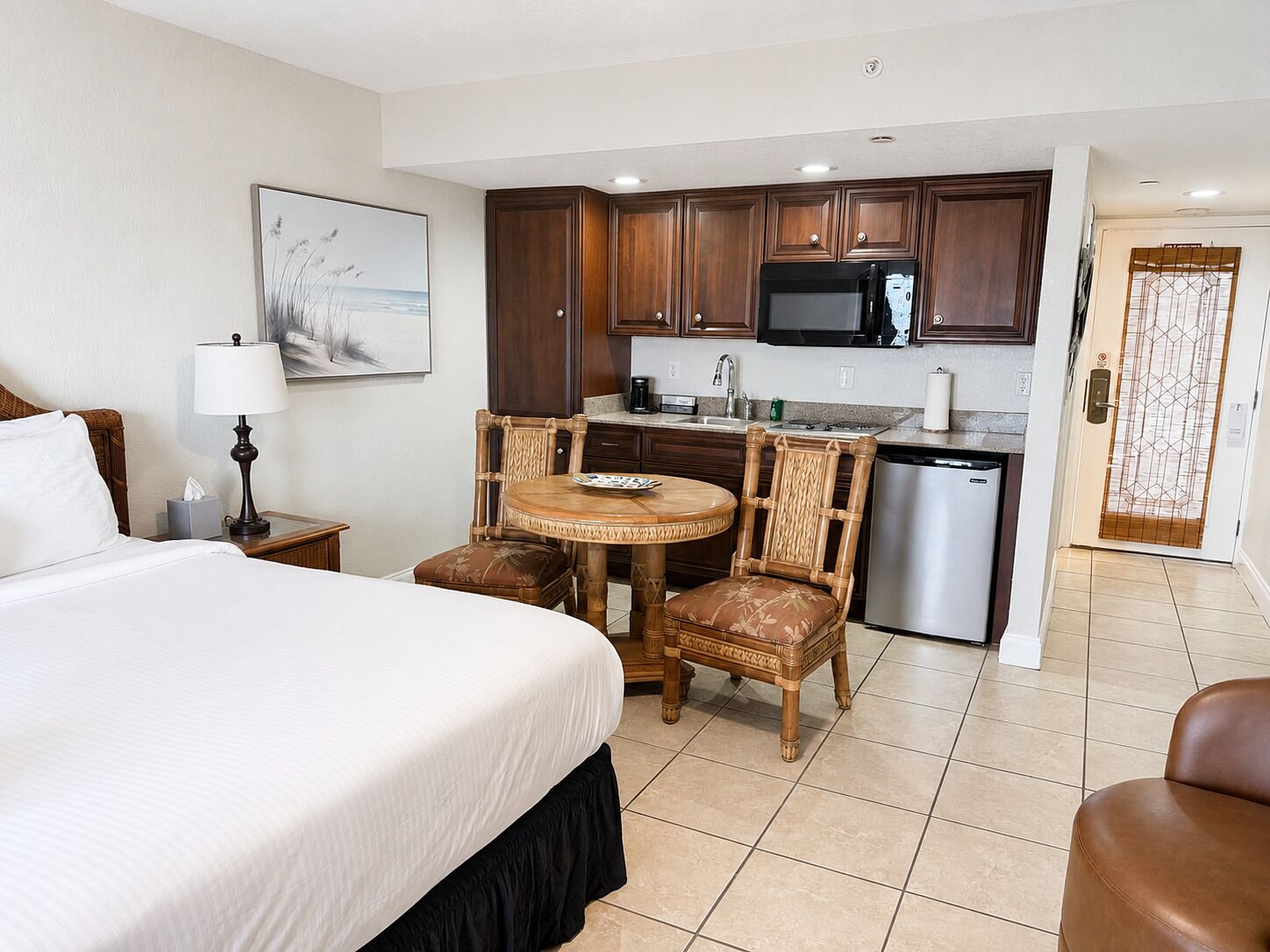 Een hotelkamer met een bed, een eettafel met stoelen, een kitchenette en een badkamer.