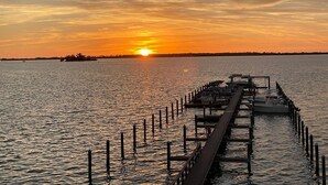 Une jetée s’avançant dans une eau calme, avec un coucher de soleil en arrière-plan.