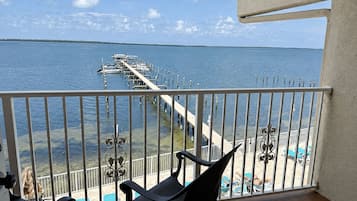 Varanda com vista para um cais e barcos, piscina e espreguiçadeiras.