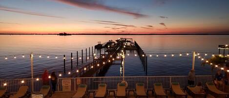 A poolside area with lounge chairs and a pier extending into the water.
