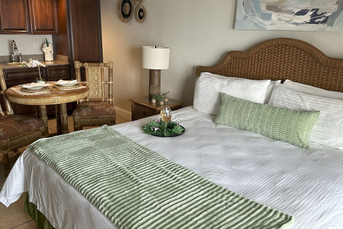 Une chambre d’hôtel avec un lit, une table à manger, des chaises, une lampe et un tableau au mur.