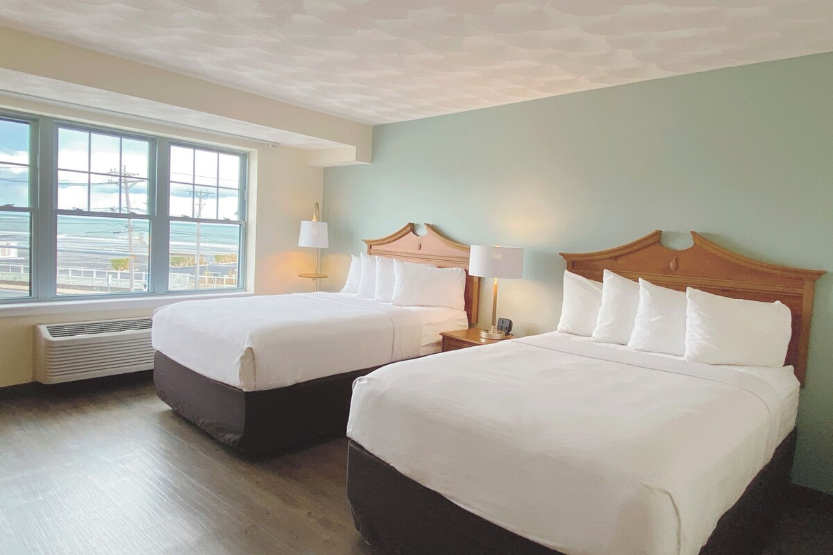A hotel room with two beds, a large window, and a view of the city.