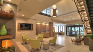 A spacious lobby with a reception desk, seating area with chairs, a staircase, and a large TV screen. - Holiday Inn & Suites Pigeon Forge Convention Center by IHG (Pigeon Forge)