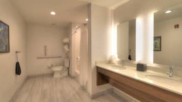 Une salle de bain moderne avec un grand miroir, deux lavabos et un espace douche.