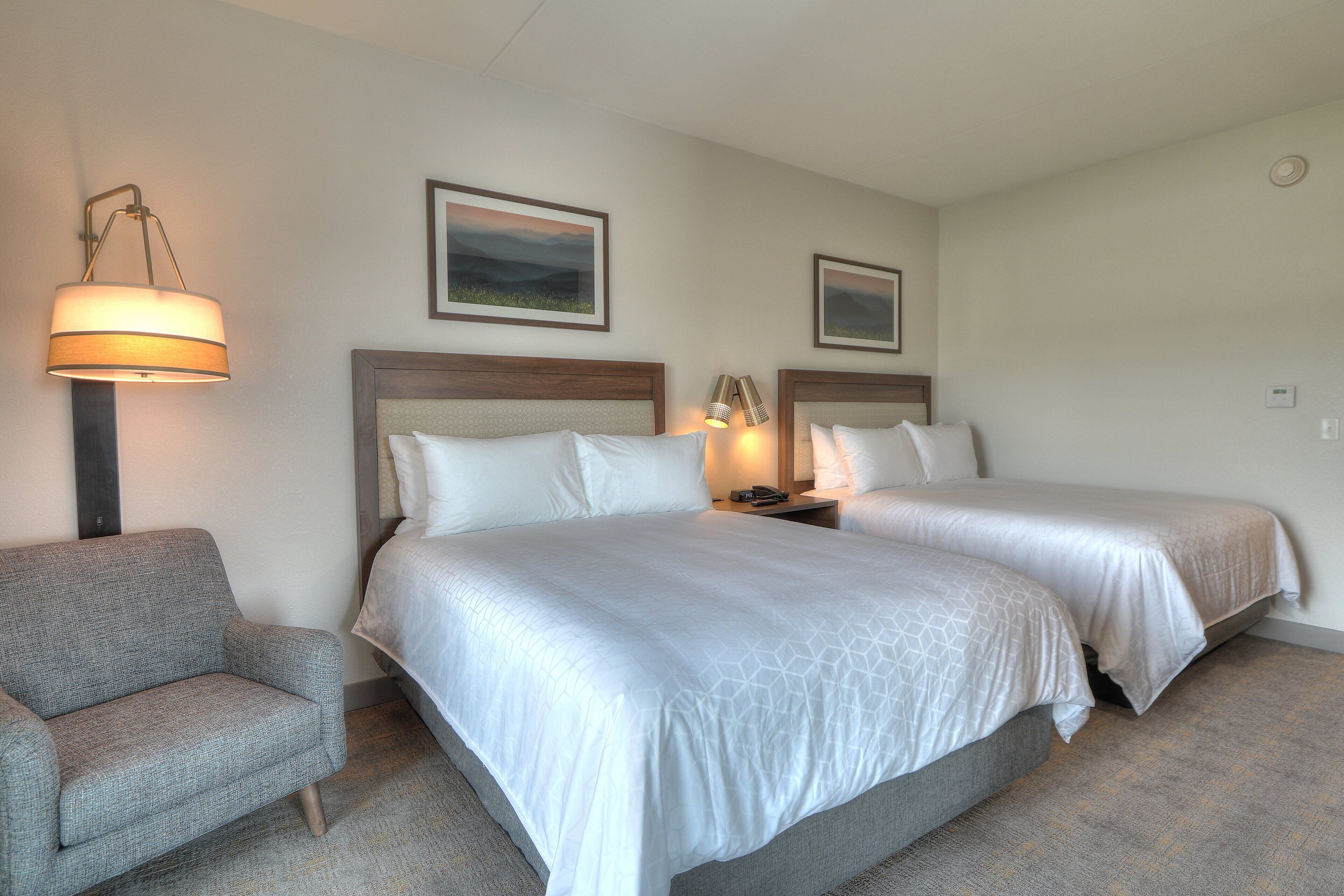 Une chambre d’hôtel avec deux lits, un canapé et une lampe.