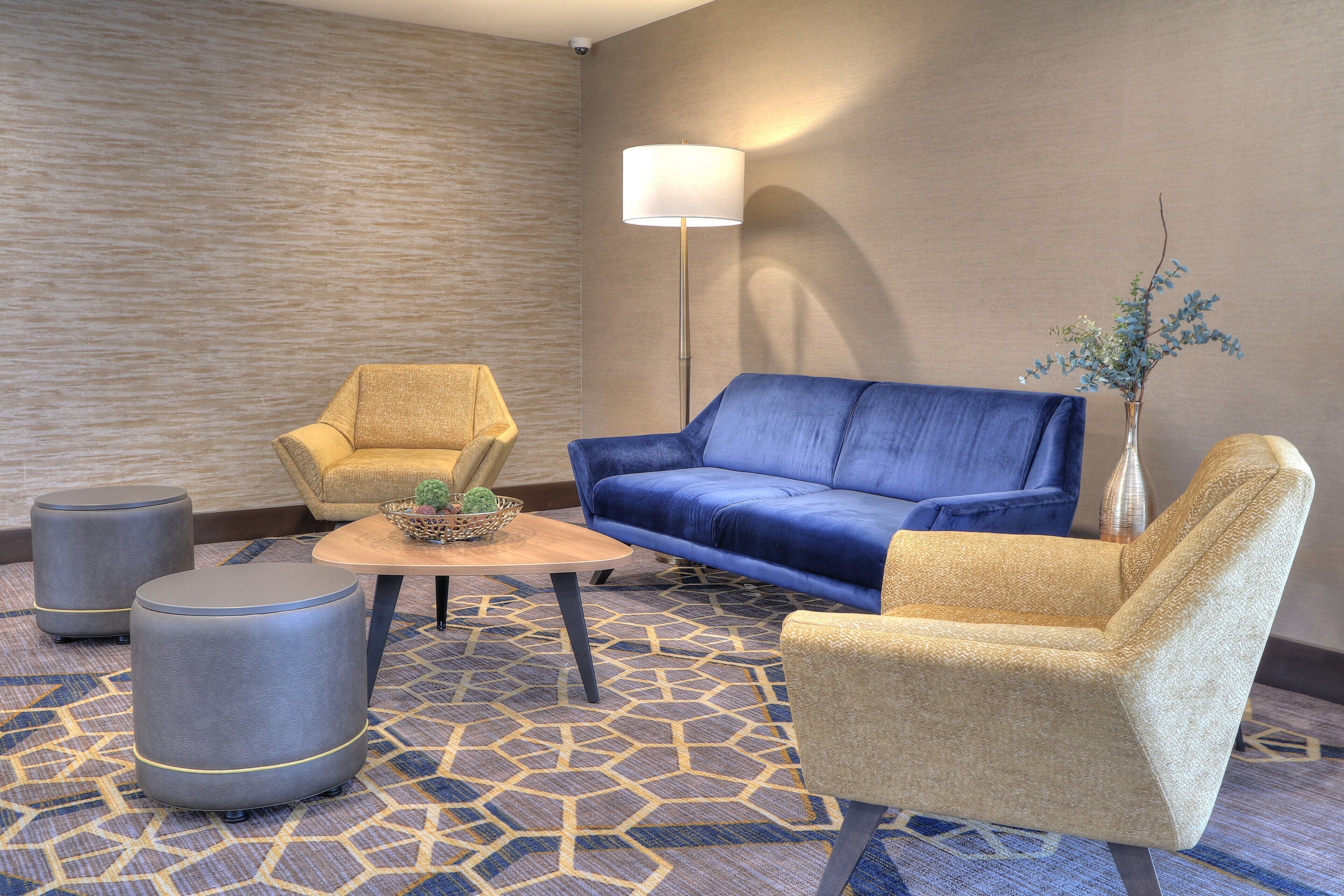 A seating area with a blue sofa, two armchairs, a coffee table, and a lamp.