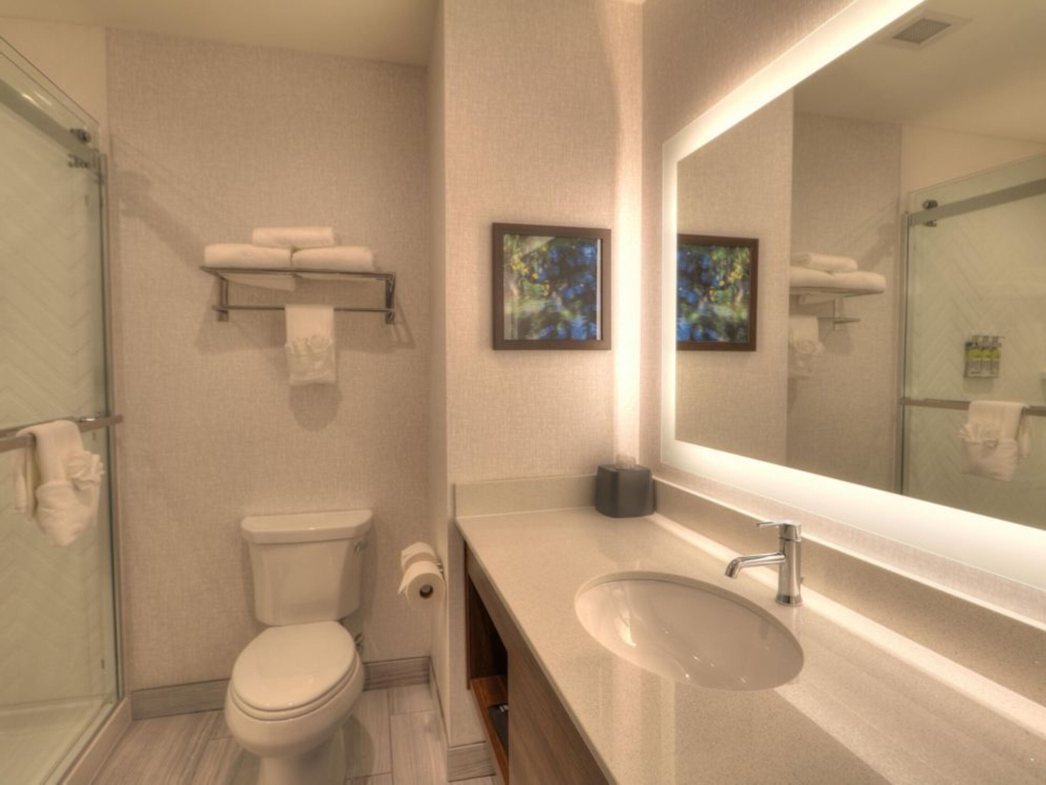 Ein modernes Badezimmer mit Toilette, Waschbecken und Duschkabine aus Glas.